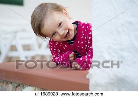 Stock Photo - Portrait of female toddler leaning forward and peeking from table. Fotosearch
