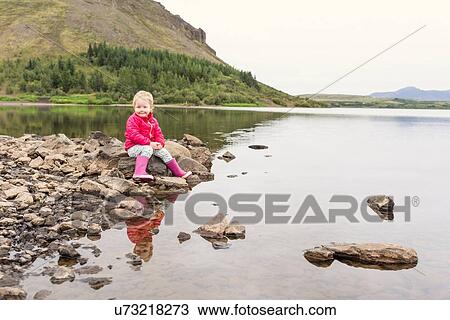 Portrait of female toddler sitting on lakeside rock, Hafravatn, Iceland View Large Photo Image Stock Image - Portrait of female toddler sitting on lakeside rock, Hafravatn, Iceland. Fotosearch