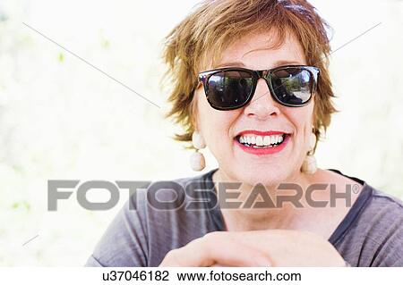 Portrait of happy mature woman wearing sunglasses View Large Photo Image Stock Image - Portrait of happy mature woman wearing sunglasses. Fotosearch