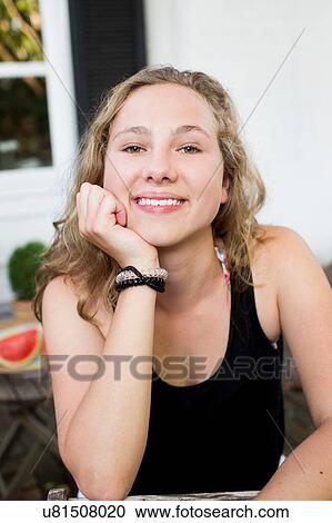 Stock Image - Portrait of happy teenage girl on patio. Fotosearch