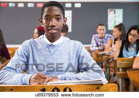 Portrait of male student, sitting at desk in classroom View Large Photo Image Stock Image - Portrait of male student, sitting at desk in classroom. Fotosearch