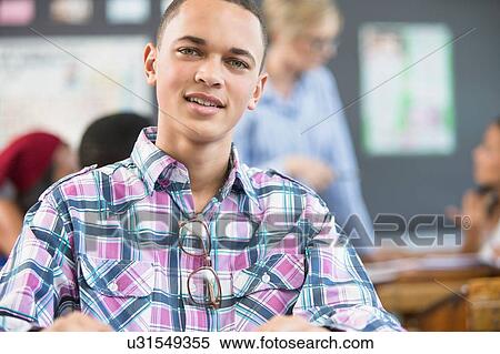 Stock Photography - Portrait of male student, sitting at desk in classroom. Fotosearch