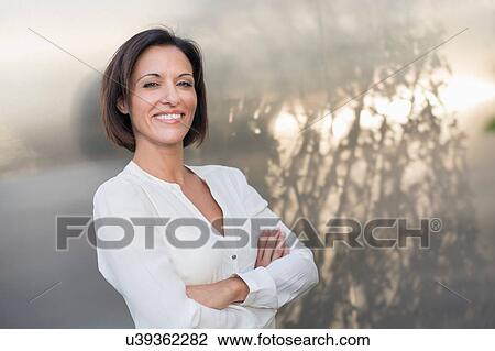 Stock Image - Portrait of mature businesswoman leaning against office building. Fotosearch