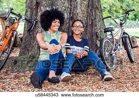 Portrait of mature woman and son sitting against park tree View Large Photo Image Stock Image - Portrait of mature woman and son sitting against park tree. Fotosearch