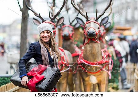 Portrait of mature woman with Christmas gift in front of reindeer display, Copenhagen, Denmark View Large Photo Image Stock Photo - Portrait of mature woman with Christmas gift in front of reindeer display, Copenhagen, Denmark. Fotosearch