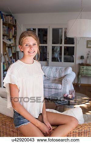 Stock Image - Portrait of pretty teenage girl in living room. Fotosearch