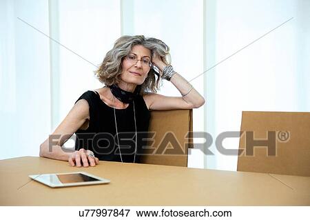 Stock Photo - Portrait of senior female designer at boardroom table. Fotosearch