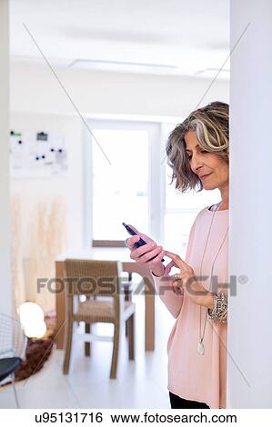 Portrait of senior female designer reading smartphone text in office View Large Photo Image Stock Photograph - Portrait of senior female designer reading smartphone text in office. Fotosearch