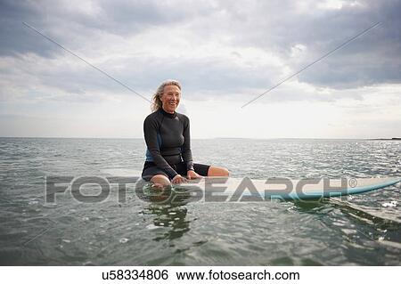 Portrait of senior woman sitting on surfboard in sea, smiling View Large Photo Image Stock Photograph - Portrait of senior woman sitting on surfboard in sea, smiling. Fotosearch