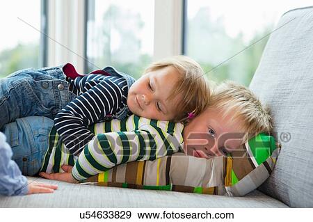 Stock Photo - Portrait of tired boy and female toddler lying on sofa. Fotosearch