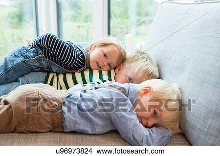 Portrait of tired boy and two toddlers lying on sofa View Large Photo Image Picture - Portrait of tired boy and two toddlers lying on sofa. Fotosearch