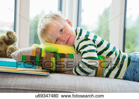 Stock Image - Portrait of tired boy lying on sofa. Fotosearch