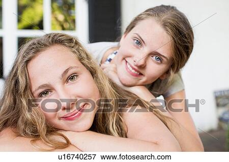 Stock Photo - Portrait of two teenage girls lying on patio. Fotosearch