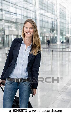 Portrait of young businesswoman at airport with wheeled suitcase View Large Photo Image Stock Image - Portrait of young businesswoman at airport with wheeled suitcase. Fotosearch