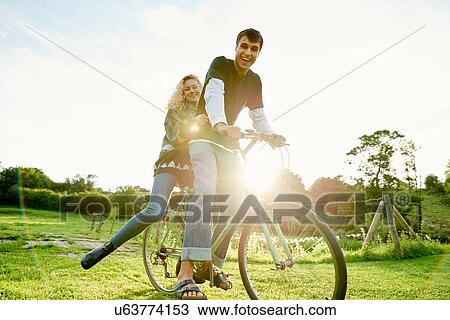 Stock Image - Portrait of young couple on bicycle. Fotosearch