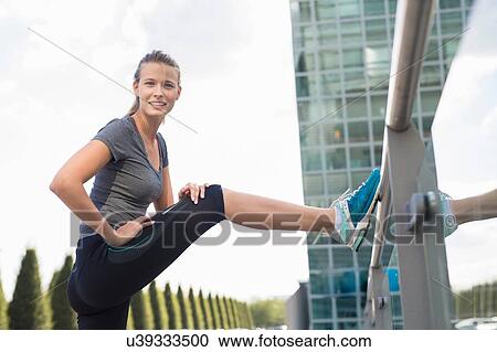 Portrait of young female runner warming up in city View Large Photo Image Stock Image - Portrait of young female runner warming up in city. Fotosearch
