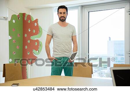 Portrait of young male designer with digital tablet in office View Large Photo Image Picture - Portrait of young male designer with digital tablet in office. Fotosearch