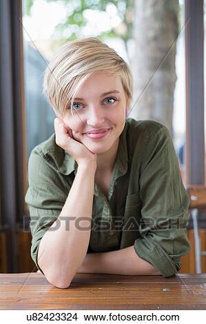 Picture - Portrait of young woman at cafe table. Fotosearch