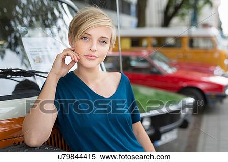 Stock Photography - Portrait of young woman leaning against campervan. Fotosearch