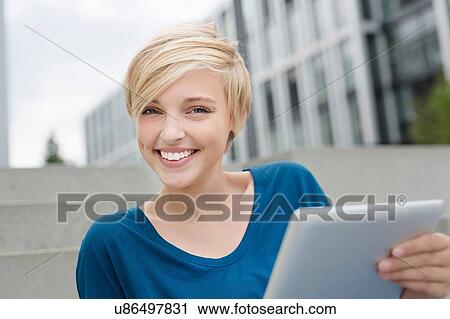 Portrait of young woman using digital tablet on city stairway View Large Photo Image Stock Image - Portrait of young woman using digital tablet on city stairway. Fotosearch
