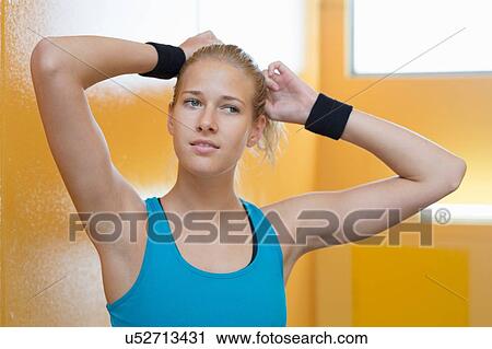 Portrait of young woman, wearing sports clothing, tying hair View Large Photo Image Stock Image - Portrait of young woman, wearing sports clothing, tying hair. Fotosearch