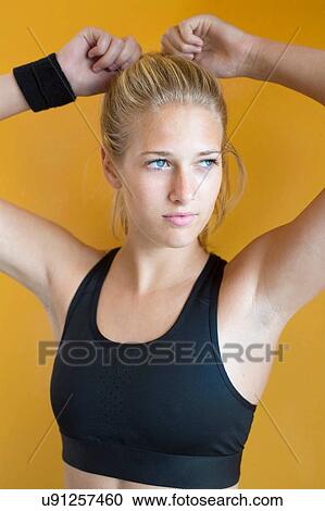 Portrait of young woman, wearing sports clothing, tying hair View Large Photo Image Stock Image - Portrait of young woman, wearing sports clothing, tying hair. Fotosearch