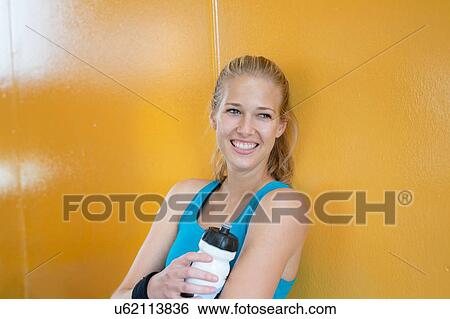 Portrait of young woman, wearing sports clothing, holding water bottle View Large Photo Image Stock Photograph - Portrait of young woman, wearing sports clothing, holding water bottle. Fotosearch