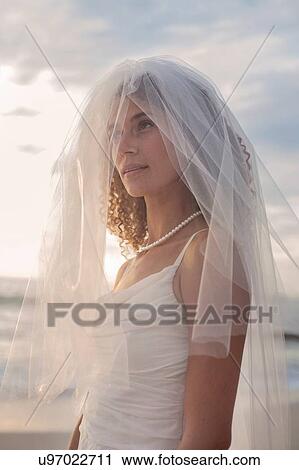 Stock Image - Portrait of young woman wearing wedding dress and veil. Fotosearch