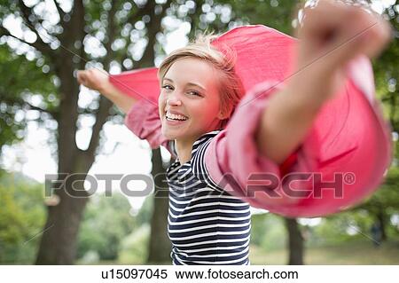 Stock Photography - Portrait of young woman with arms open wearing pink shirt. Fotosearch
