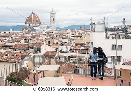 Stock Photograph - Rear view of lesbian couple standing of roof terrace looking at view of Giotto's Campanile and Florence Cathedral, Tuscany, Italy. Fotosearch