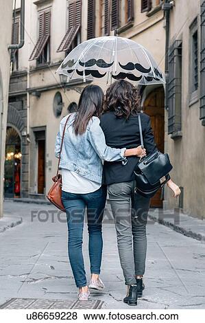Rear view of lesbian couple walking together in street holding umbrella, Florence, Tuscany, Italy View Large Photo Image Stock Photo - Rear view of lesbian couple walking together in street holding umbrella, Florence, Tuscany, Italy. Fotosearch