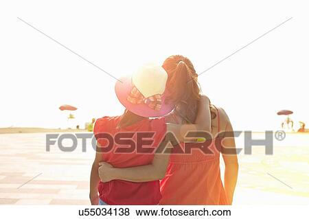 Stock Photo - Rear view of mid adult woman and daughter on beach, Zhuhai, Guangdong, China. Fotosearch