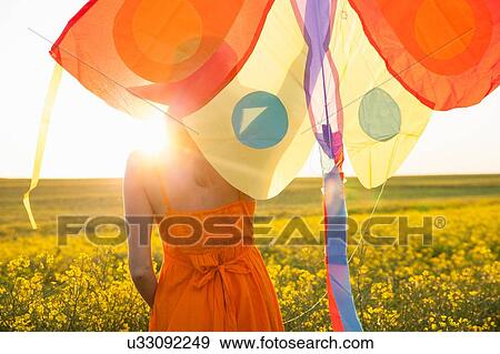 Rear view of mid adult woman in canola field arm raised holding kite View Large Photo Image Stock Photo - Rear view of mid adult woman in canola field arm raised holding kite. Fotosearch