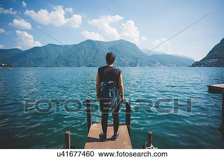 Rear view of mid adult woman looking out from pier, Lake Lugano, Switzerland View Large Photo Image Stock Image - Rear view of mid adult woman looking out from pier, Lake Lugano, Switzerland. Fotosearch