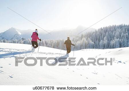 Stock Photo - Rear view of senior couple using walking poles on snow covered landscape, Sattelbergalm, Tyrol, Austria. Fotosearch