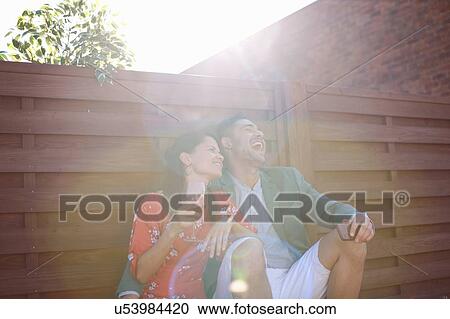 Relaxed mid adult couple laughing and drinking at rooftop party View Large Photo Image Stock Image - Relaxed mid adult couple laughing and drinking at rooftop party. Fotosearch
