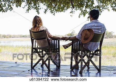 Romantic couple holding hands whilst sitting at safari lodge, Kafue National Park, Zambia View Large Photo Image Stock Image - Romantic couple holding hands whilst sitting at safari lodge, Kafue National Park, Zambia. Fotosearch