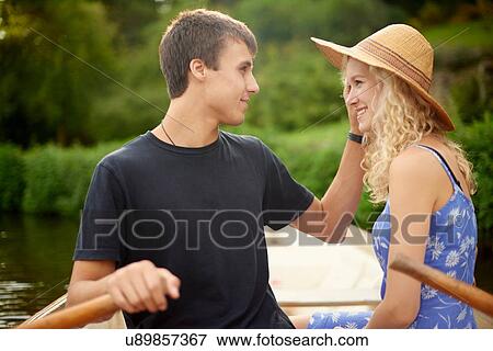 Stock Photo - Romantic young couple rowing boat on rural river. Fotosearch