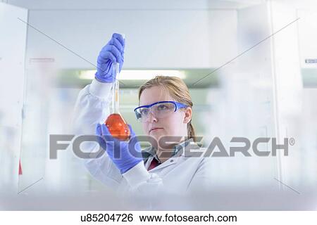 Stock Photograph - Scientist inspecting coloured samples in testing laboratory. Fotosearch