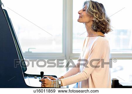 Stock Photo - Senior female designer playing on games machine in office. Fotosearch