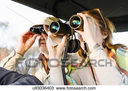 Stock Image - Senior man and daughter looking out through binoculars on safari, Kafue National Park, Zambia. Fotosearch