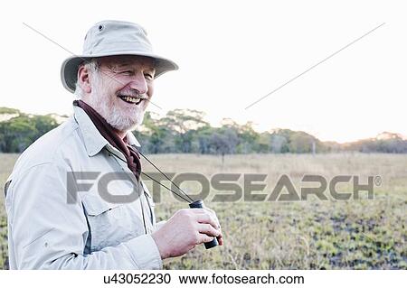 Senior man holding binoculars on safari, Kafue National Park, Zambia View Large Photo Image Stock Image - Senior man holding binoculars on safari, Kafue National Park, Zambia. Fotosearch