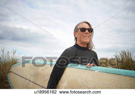 Senior woman at beach, carrying surfboard View Large Photo Image Stock Image - Senior woman at beach, carrying surfboard. Fotosearch