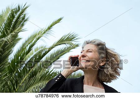 Stock Photograph - Senior woman chatting on smartphone. Fotosearch