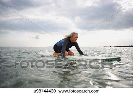 Senior woman on surfboard in sea, paddleboarding View Large Photo Image Stock Image - Senior woman on surfboard in sea, paddleboarding. Fotosearch