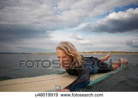Senior woman on surfboard in sea, paddleboarding View Large Photo Image Stock Photo - Senior woman on surfboard in sea, paddleboarding. Fotosearch