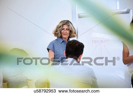 Senior woman presenting to business team in office View Large Photo Image Stock Image - Senior woman presenting to business team in office. Fotosearch