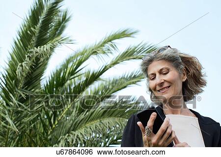 Stock Photograph - Senior woman reading smartphone texts. Fotosearch