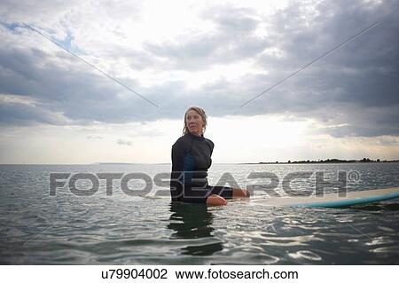 Senior woman sitting on surfboard in sea View Large Photo Image Stock Image - Senior woman sitting on surfboard in sea. Fotosearch