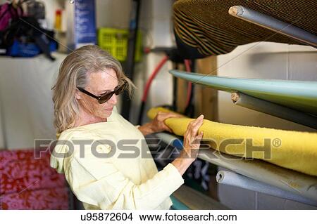 Senior woman taking surfboard from shelf View Large Photo Image Picture - Senior woman taking surfboard from shelf. Fotosearch
